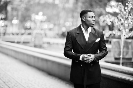 Portrait of young and handsome african american businessman in suit walking on cemter of city with garlands.の写真素材