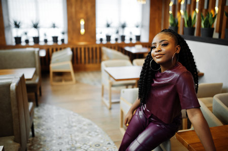 Beautiful african american woman in red leather costume pose at restaurant.の写真素材