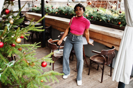Urban young african american woman in pink top and gray jeans and sunglasses with handbag. Afro...