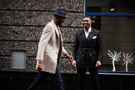Two fashion black men walking on street. Fashionable portrait of african american male models. Wear...
