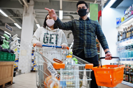 Asian couple wear in protective face mask shopping together in supermarket during pandemic.の写真素材
