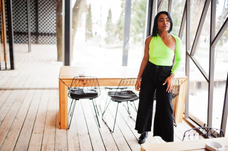 Fashionable african american woman in a light green top and black pants pose.