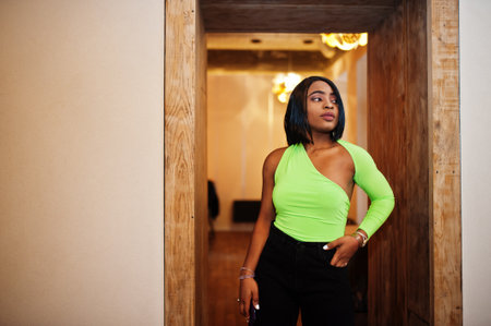 Fashionable african american woman in a light green top and black pants pose.の写真素材