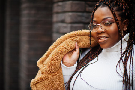 Glamorous african american woman in warm fur coat, eyeglasses pose at street.の写真素材