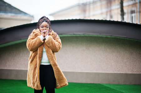Glamorous african american woman in warm fur coat pose at street.