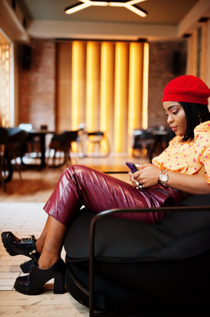 Elegant afro american woman in red french beret, big gold neck chain polka dot blouse and leather...