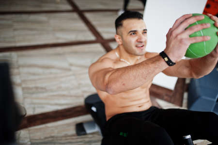 Muscular arab man training in modern gym. Fitness arabian men with naked torso doing exercises with...