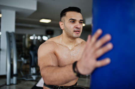 Muscular arab man training in modern gym. Fitness arabian men with naked torso doing exercises with...