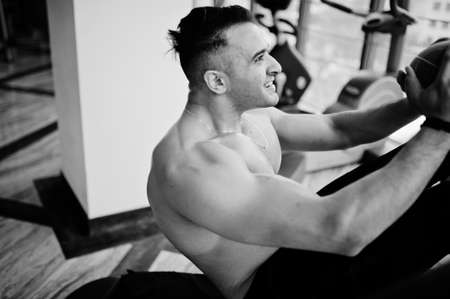 Muscular arab man training in modern gym. Fitness arabian men with naked torso doing exercises with ball.の写真素材