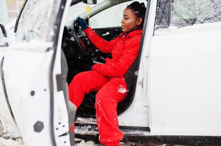 African american woman in red hoodie sitting inside car at winter snowy day.の写真素材