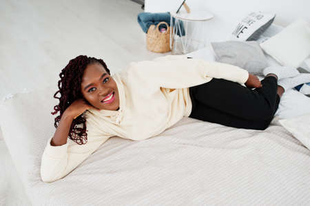 African woman in hoodie lying on the bed at home.の写真素材