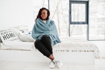 African woman cover by plaid blanked at home.の写真素材