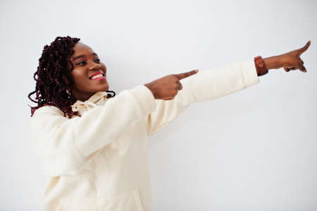 African woman in hoodie stand against white wall and show fingers right.の写真素材