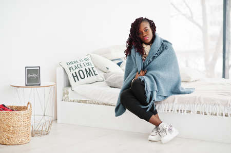 African woman cover by plaid blanked at home.の写真素材