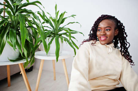 African woman sitting near greenery at home.の写真素材