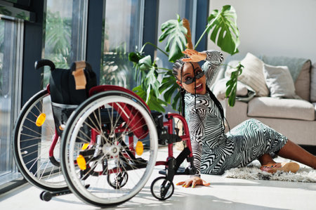 Young disabled African American woman fall from wheelchair at home.