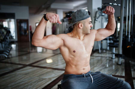 Fit and muscular arabian man doing workouts in gym.