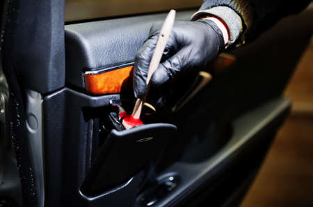 Man in uniform and respirator, worker of car wash center, cleaning car interior cleaning brush. Car...