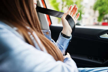 Gorgeous woman sitting inside car interior and tie belt.