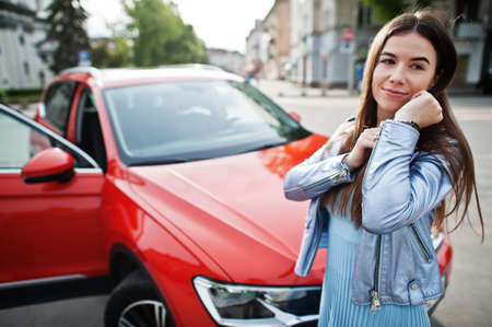 Outdoor photo of gorgeous woman posing near orange suv car.