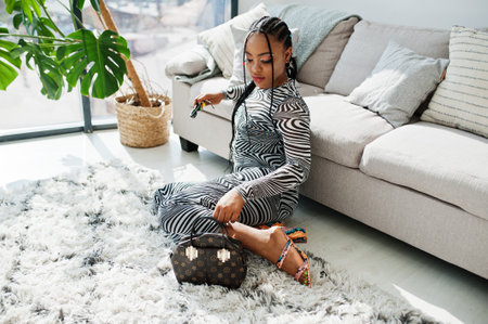 Afro woman in zebra dress sitting indoor. Stylish portrait of african american model in sunglasses.の写真素材
