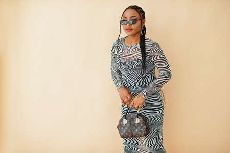 Afro woman in zebra dress against yellow background. Stylish portrait of african american model in studio.の写真素材