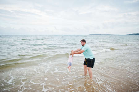 Summer vacations. Parents and people outdoor activity with children. Happy family holidays. Father with baby daughter on sea sand beach.の写真素材