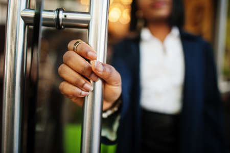 Hand with ring of african chic business girl in coat open door.の写真素材
