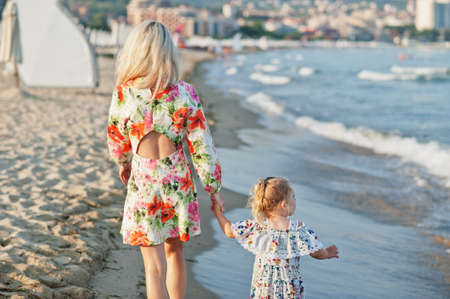 Mother and beautiful daughter having fun on the beach. Portrait of happy woman with cute little girl...