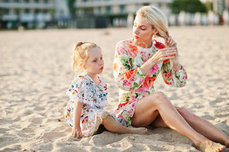 Mother and beautiful daughter having fun on the beach. Portrait of happy woman with cute little girl...
