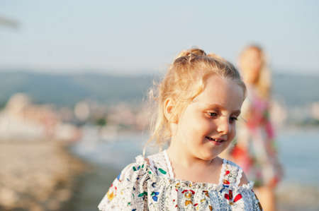 Mother and beautiful daughter having fun on the beach. Portrait of happy woman with cute little girl...