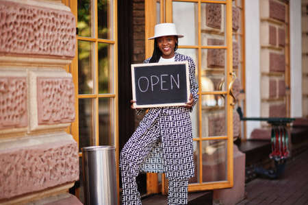 African american woman hold open welcome sign board in modern cafe coffee shop ready to service, restaurant, retail store, small business owner.の写真素材