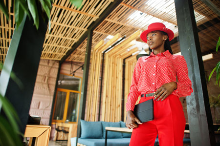 Pretty braids business african american lady bright bossy person friendly wear office red shirt, hat and trousers, hold tablet on hands.の写真素材