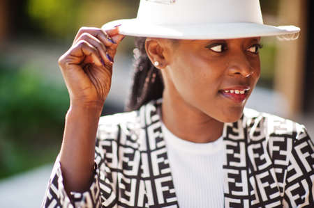 Beautiful african american woman natural makeup wear fashion clothes casual black and white dress code office style total blouse and pants suit and hat.の写真素材
