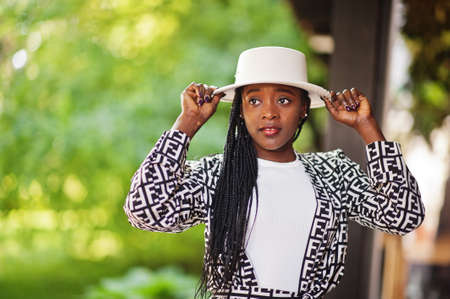Beautiful african american woman natural makeup wear fashion clothes casual black and white dress code office style total blouse and pants suit and hat.の写真素材