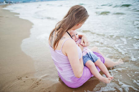 Summer vacations. Parents and people outdoor activity with children. Happy family holidays. Pregnant mother with baby daughter on sea sand beach.の写真素材