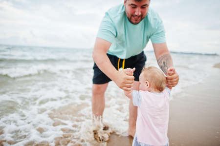 Summer vacations. Parents and people outdoor activity with children. Happy family holidays. Father with baby daughter on sea sand beach.の写真素材