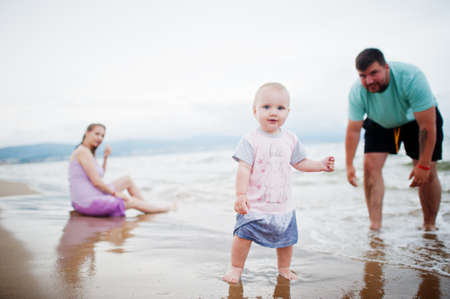 Summer vacations. Parents and people outdoor activity with children. Happy family holidays. Father, pregnant mother, baby daughter on sea sand beach.の写真素材