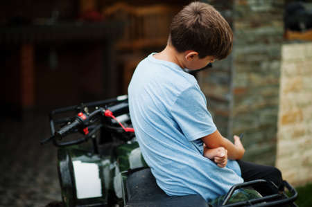 Boy in four-wheller ATV quad bike with mobile phone.の写真素材
