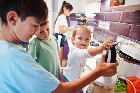 Mother with kids cooking at kitchen, happy children's moments. Work with a blender.の写真素材