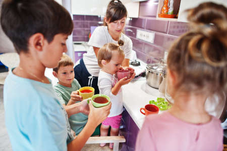 Mother with kids drink compote at kitchen, happy children's moments.の写真素材