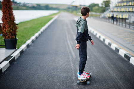 Teenager boy in a sports suit rides on longboard.の写真素材