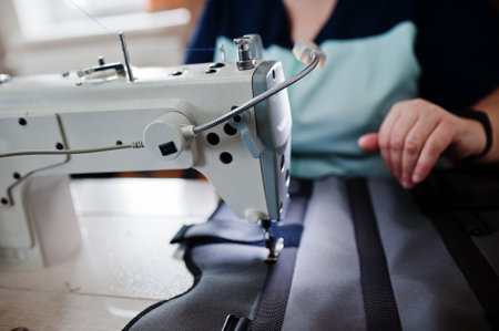 Female hands stitching fabric on professional manufacturing machine at workplace. Sewing process.の写真素材