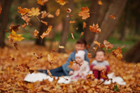 Blur photo of happy family of three kids at autumn leaves park.