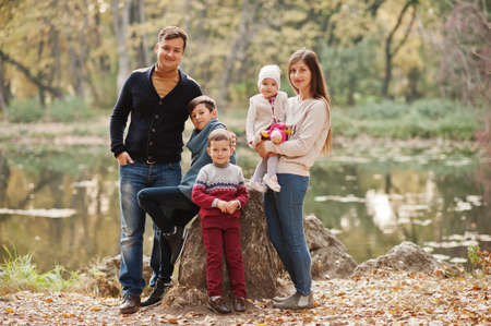 Happy family at autumn leaves park. Three kids.の写真素材
