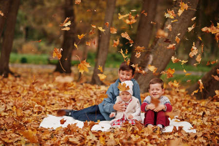 Happy family of three kids at autumn leaves park.の写真素材