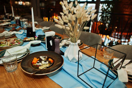 Beautifully laid tables with food, glasses and appliances in restaurant.