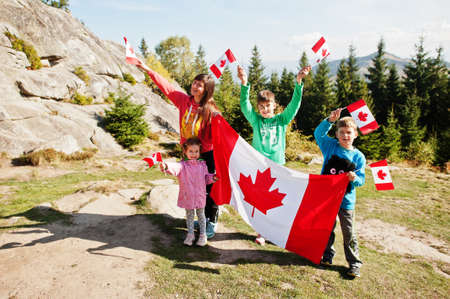 Happy Canada Day. Family of mother with three kids hold large Canadian flag celebration in...