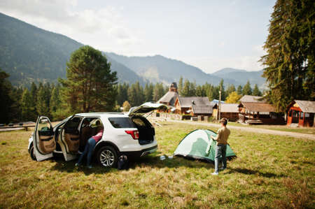 Boy sets up a tent. Traveling by car in the mountains, atmosphere concept.の写真素材