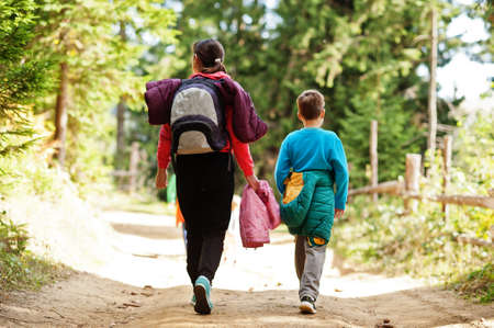 Back of mother with three kids walking on wood mountains. Family travel and hiking with childrens.の写真素材